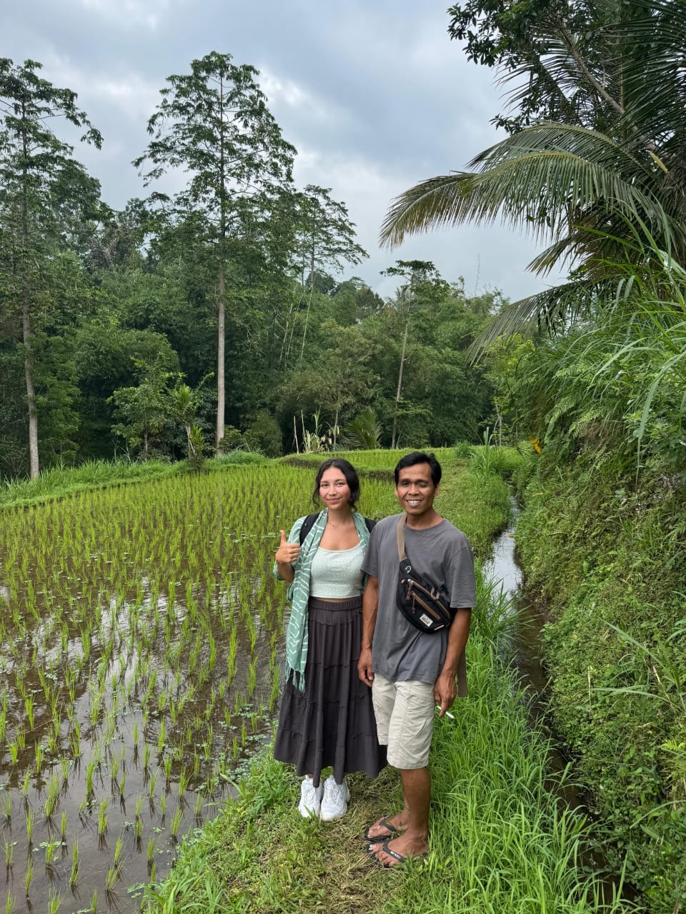 Guest and local guide standing beside a Tetebatu rice paddy