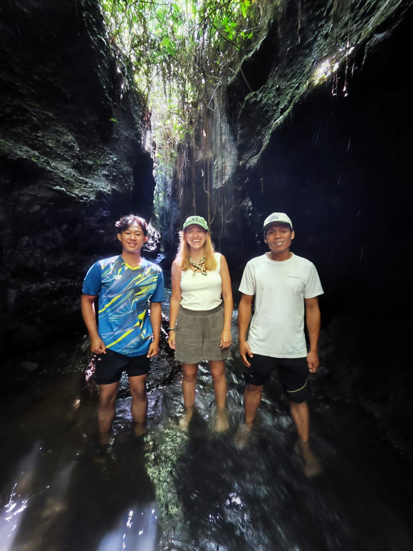 Guests and local guide inside a hidden slot-canyon waterfall in Tetebatu