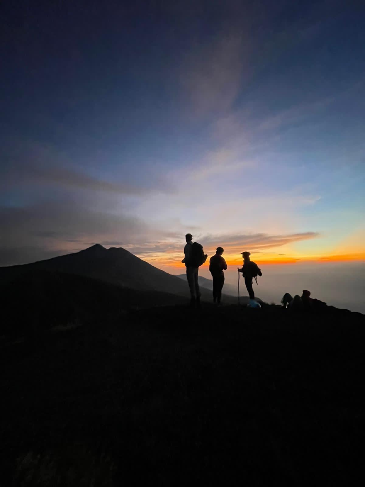 Trekkers silhouetted at sunset on the crater rim